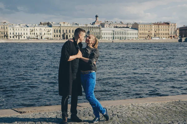 bir adam bir kız waterfront ve eski binalar arka plan üzerinde hugs.