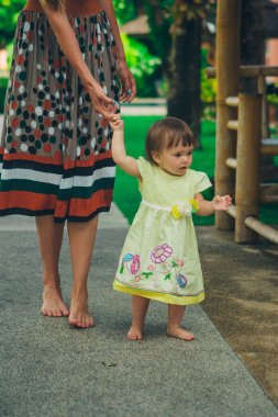 Sevimli bebek yürümek ve ilk adımlarını yapmak öğrenme. Annem elini tutuyor. Çocuğun ayakları yakın yukarı, kopyalama alanı