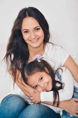 Annenin kollarında bebek. Beyaz arka planda çocuk tutan kadın. Kız için moda.
