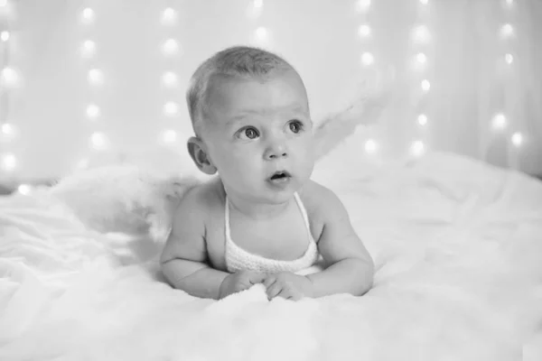 Boy with his mouth open is lying on a white background with wings behind his back. Angel Cupid looks up — Stock Photo, Image