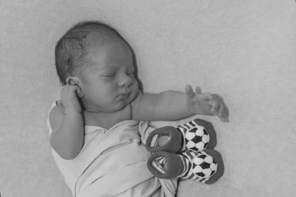 Newborn baby and baby booties with soccer ball pattern — Stock Photo, Image