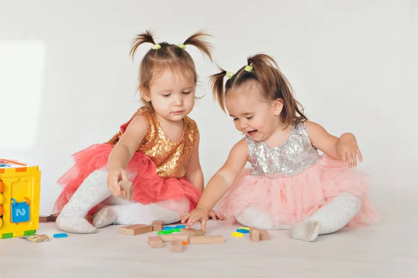 Duas meninas brincando no chão em um fundo branco — Fotografia de Stock