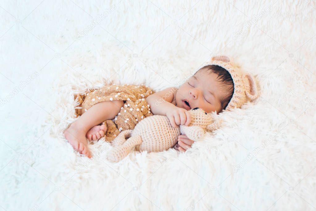 newborn baby sleeping with a toy next to the knitted teddy bear