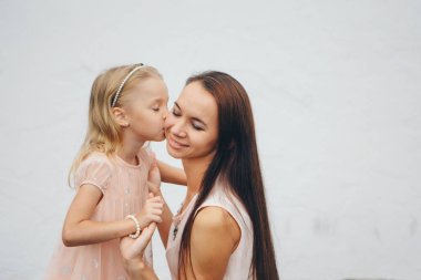 Annenin kollarında bebek. Beyaz arka planda çocuk tutan kadın. Kız için moda.