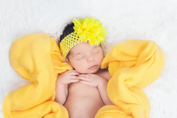 Un enfant avec un bandage jaune avec une fleur sur la tête dans une couverture jaune en forme de fleur — Photo