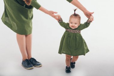 Sevimli bebek yürümek ve ilk adımlarını yapmak öğrenme. Annem elini tutuyor. Çocuğun ayakları yakın yukarı, kopyalama alanı