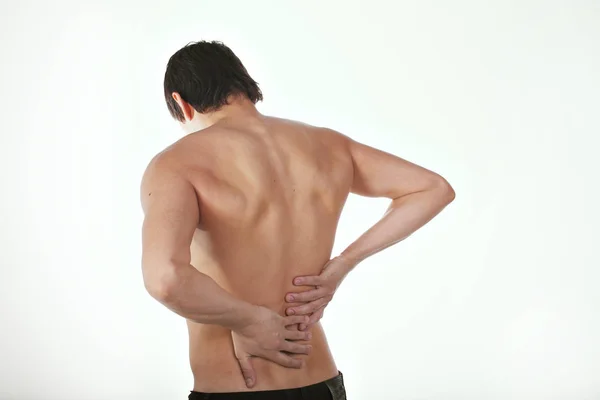 Dolor de espalda: un hombre sobre un fondo blanco sosteniendo su torso dolorido —  Fotos de Stock