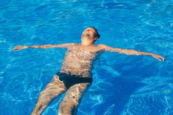 Gebruinde man op vakantie zwemmen in het zwembad — Stockfoto