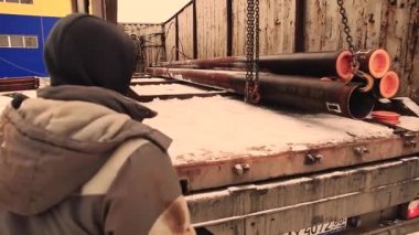 Metal boru kamyona yükleniyor. bir büyük santral Vinci kişi metal bir depoda çalışıyor.