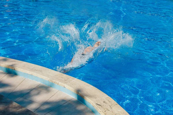 Egy ember ugrik a medencébe. A vízben úszó — Stock Fotó