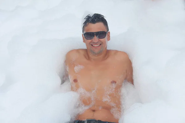 L'homme en lunettes s'amuse dans la mousse blanche — Photo