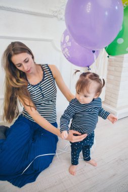 beyaz bir arka planda annesinin kollarında çocuk. Kollarında bir çocuk ile bir kadın Festival balonlar tutarak