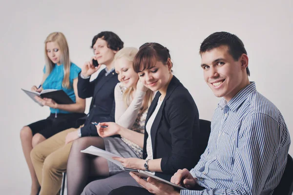 Business people waiting in queue sitting in row holding smartphones and cvs, human resources, employment and hiring concept — Stock Photo, Image