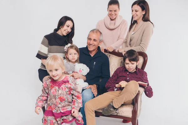 Groupe de personnes sur fond blanc : adultes et enfants avec des jouets assis sur le même canapé — Photo