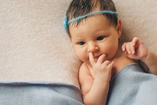 Portrait of a newborn baby with a pen on his face: a finger in his nose — Stock Photo, Image