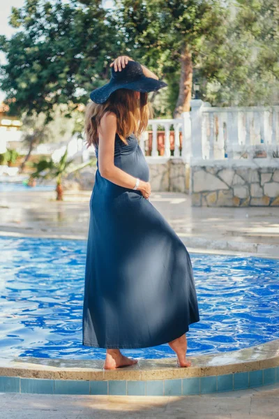 Gravid kvinne med langt hår i blå kjole som poserer i vann – stockfoto