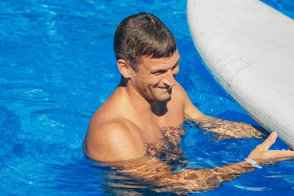 Gebruinde man op vakantie zwemmen in het zwembad — Stockfoto