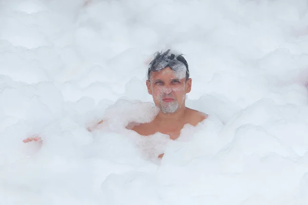 L'homme en lunettes s'amuse dans la mousse blanche — Photo