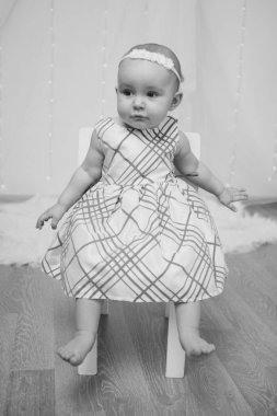 bir elbise, küçük bir kız gülümser ve bir sandalyeye oturur