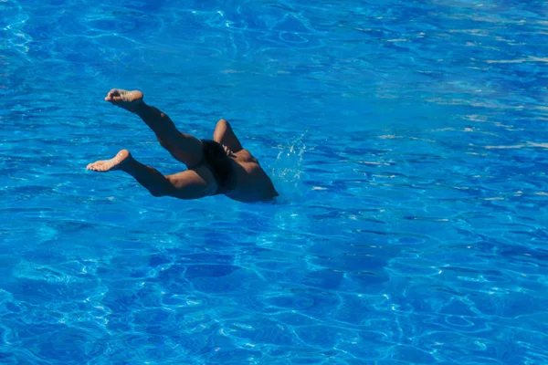 Een man springt in het zwembad. Zwemmer in het water — Stockfoto