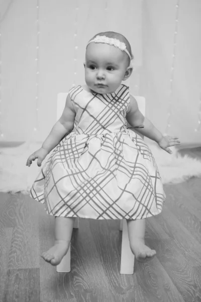 Маленькая девочка в платье сидит на стуле и улыбается — стоковое фото