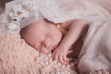 Yeni doğmuş bir bebek inci ve çiçek bir calico battaniye altında uyur