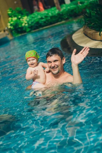 Un homme avec un enfant nageant dans la piscine. Papa avec sa fille dans l'eau — Photo