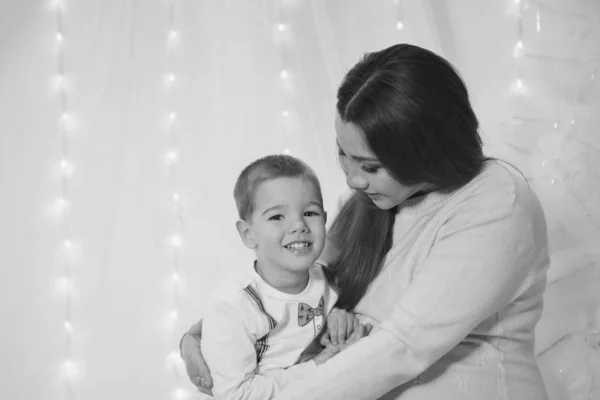 The child in the arms of his mother on the background of lights and decorative elements — Stock Photo, Image