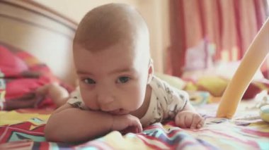 Yeni doğmuş bir bebek midesi üzerinde yatıyor ve başını tutmayı öğrenir. Çocuk kameraya bakıyor.