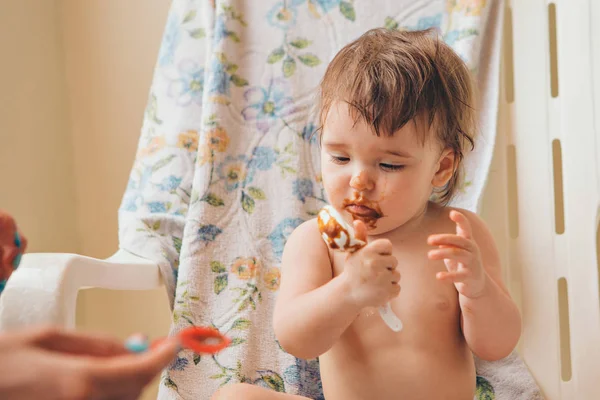 Porträt eines Kindes, das Babynahrung aus dem Löffel isst. Schmutziges Gesicht beim Essen — Stockfoto