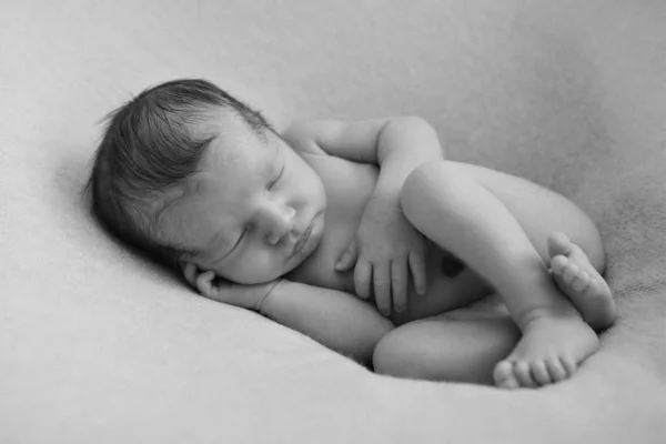 Nakna nyfött barn sover som uppkrupen i en boll — Stockfoto