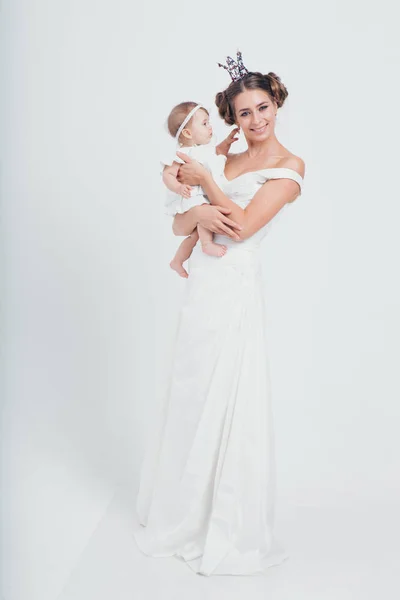母親の腕の中の赤ん坊。白い背景に子供を抱いている女性。女の子のためのファッション。王女と女王 — ストック写真