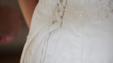 nedime elbisesi ile gelin yardım. gelinin dantel elbise. Nedime gelinliği üzerine yay bağlama. Kadının elleri gelin korsesine ipek kurdele bağlar. Dantel yardım
