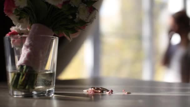 Zwei Goldene Eheringe Auf Dem Tisch Neben Blumen Brautstrauß — Stockvideo