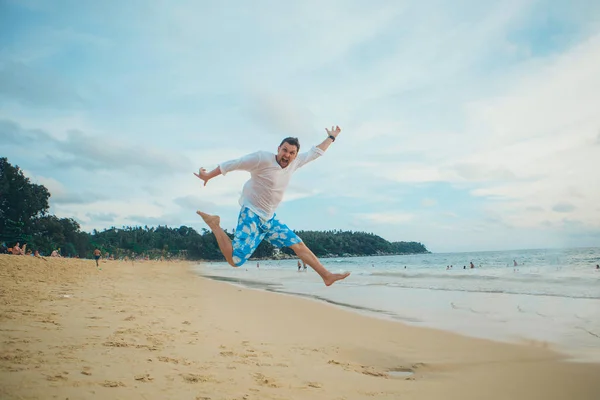 Człowiek skoki szczęśliwy na plaży z błękitne niebo i morze w tle — Zdjęcie stockowe