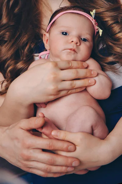 Il bambino tra le braccia della madre su sfondo bianco. Una donna con un bambino tra le braccia accanto a un grande fiore — Foto Stock