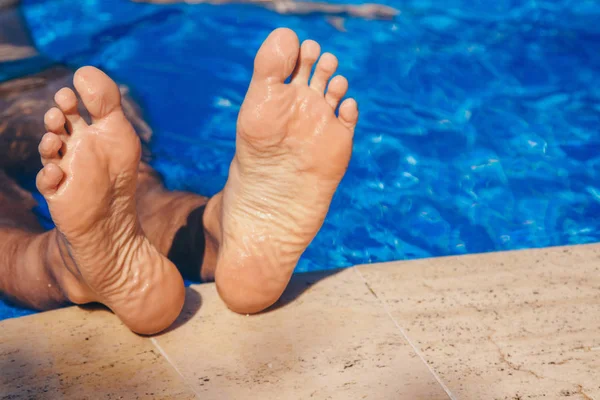 Zostań w ośrodku. Męskie nogi na dużym tle wodnym. Facet pływa w basenie. koncepcja rekreacji, relaksu, turystyki. — Zdjęcie stockowe