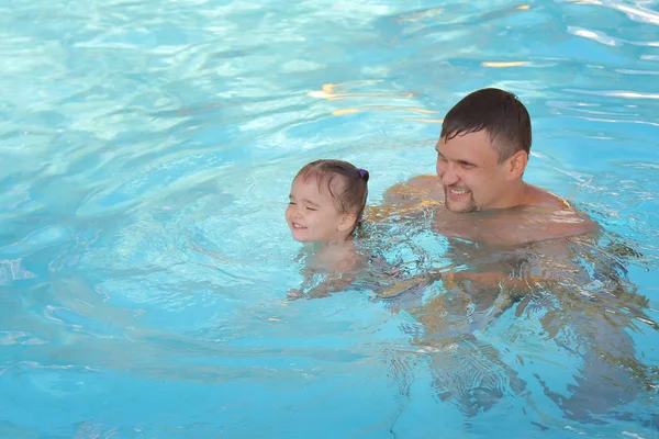 Un homme avec un enfant nageant dans la piscine. Papa avec sa fille dans l'eau — Photo