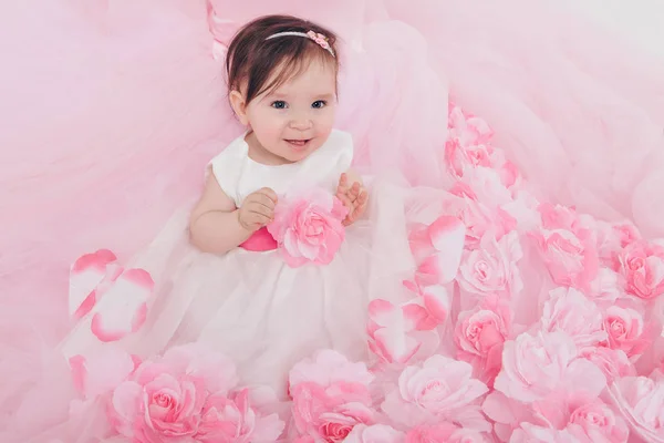 El concepto de un estilo de vida saludable, la protección de los niños, ir de compras - una niña con un vestido rosa se sienta en el suelo sobre el fondo de las flores. Niño promueve ropa de los niños —  Fotos de Stock