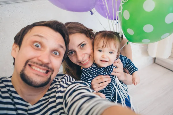 partide aile. renkli topları arasında beyaz bir arka plan üzerinde yetişkin ve çocuklar doğum günü kutlamak. erkek, kadın ve çocuk selfie çekmek