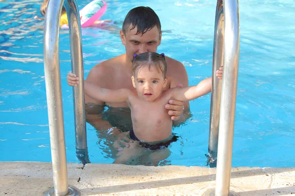 Un homme avec un enfant nageant dans la piscine. Papa avec sa fille dans l'eau — Photo