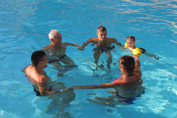 Le concept de sport, de loisirs, de mode de vie sain - 5 personnes nagent dans la piscine en formant un cercle. Les gens dans l'eau se tenant la main — Photo