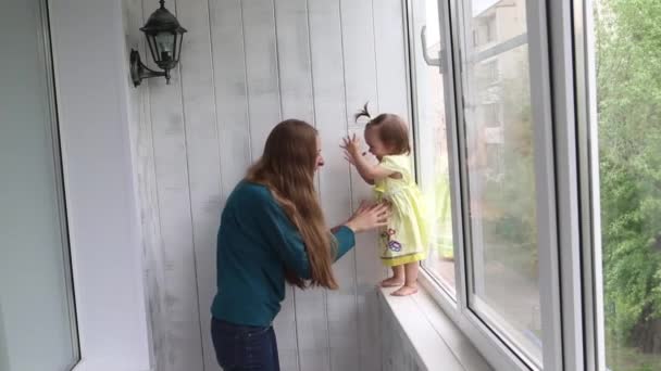 小さな女の子は 彼女の母親の手に窓からジャンプすることを学びます 女性は子供をキャッチ — ストック動画
