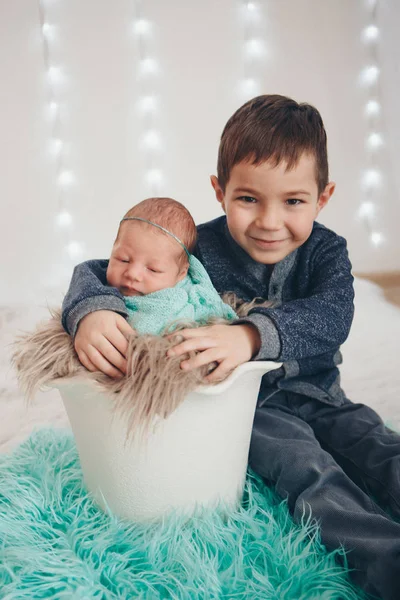 El concepto de un estilo de vida saludable, la protección de los niños, ir de compras - un adolescente con un bebé recién nacido jugando juntos. Niños felices: hermano y hermana sobre fondo blanco —  Fotos de Stock