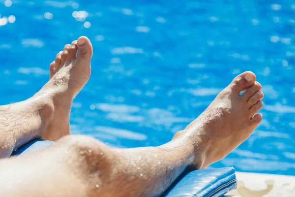 Stay at the resort. Men's legs on a large water background . Man swimming in the pool. he concept of recreation, relaxation, tourism. — Stock Photo, Image