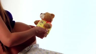 sağlıklı yaşam kavramı, annelik, bir bebek ile oynarken - bir Kadın karnına yakın bir Teddy ayı tutarken hamile.