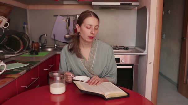 Dziewczyna Szlafrok Kulki Śniadanie Mlekiem Czyta Książkę Rano Czerwonej Kuchni — Wideo stockowe