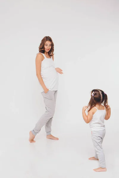 Mamá y su hija se divierten sobre un fondo blanco. Mujer embarazada y niño juegan juntos. concepto de infancia, salud, FIV — Foto de Stock