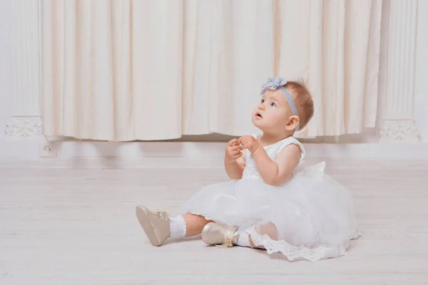 A little girl in a dress sits on the floor on a white background. Child promotes children's clothes — Stock Photo, Image