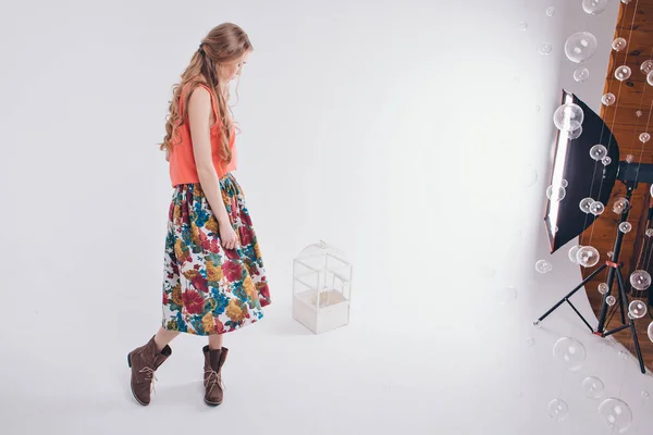 Рекламний одяг та предмети інтер'єру: дівчина в кольоровій спідниці та взуття на білому тлі поруч з кліткою для птахів. Маннекін . — стокове фото